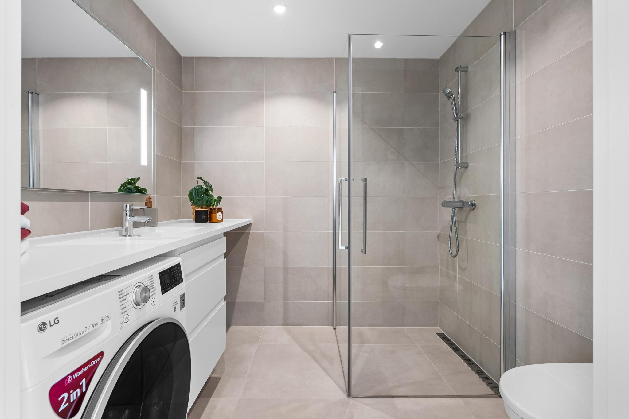 Elegant og innbydende bad med gulvvarme, downlights, romslig dusjsone og servant med bred benk og underskap.